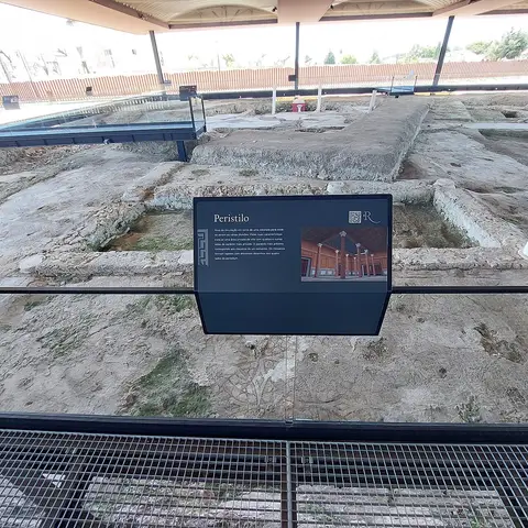 Ruínas do peristilo da Villa Romana de Rio Maior, cobertas por estrutura de proteção, com painel informativo