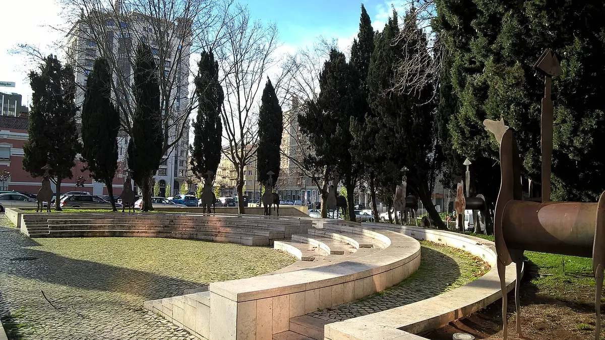 Jardim com anfiteatro de pedra, relva, ciprestes e esculturas de cavaleiros em metal