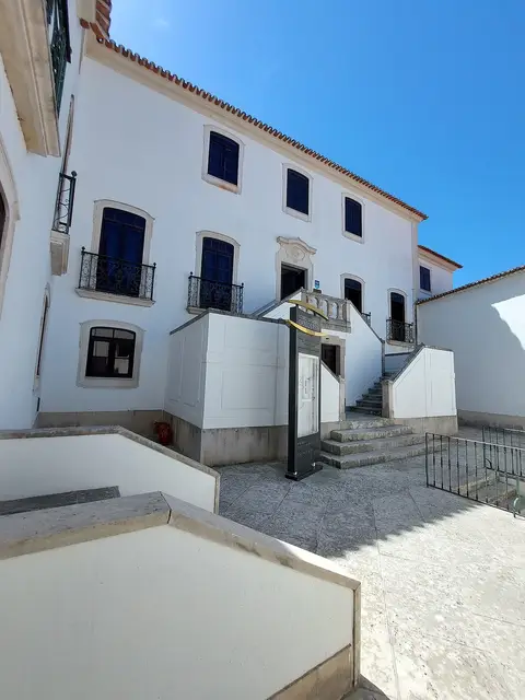 Fachada branca do Museu Municipal Carlos Reis, com escadaria de acesso à entrada e céu azul.