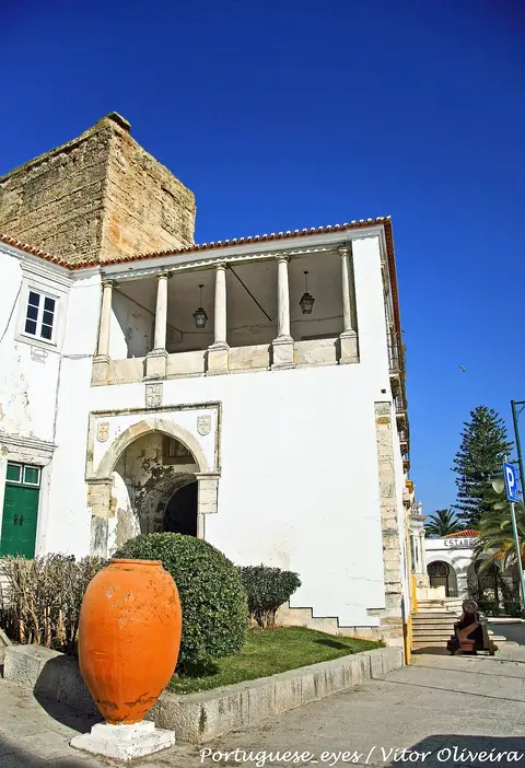 Edifício histórico branco com varanda de colunas e talha de barro à frente, em Moura