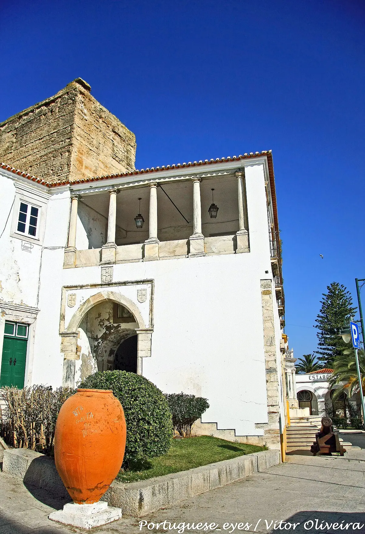 Edifício histórico branco com varanda de colunas e talha de barro à frente, em Moura