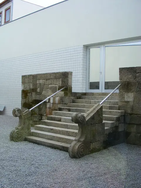 Escadaria de granito com volutas junto a parede branca no pátio do Museu de Penafiel