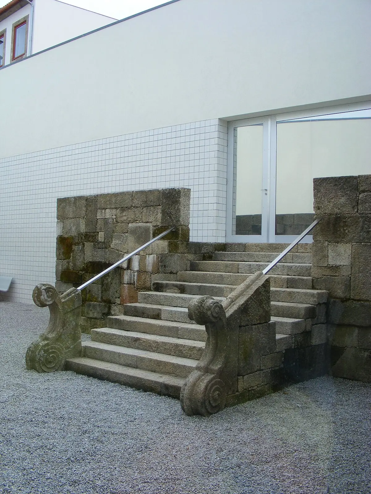 Escadaria de granito com volutas junto a parede branca no pátio do Museu de Penafiel