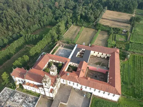 Vista aérea do Mosteiro de São Martinho de Tibães, com claustros, telhados vermelhos e cercas verdes em redor.