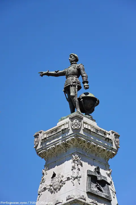 Estátua de bronze do Infante Dom Henrique no topo do monumento, sobre céu azul, no Porto