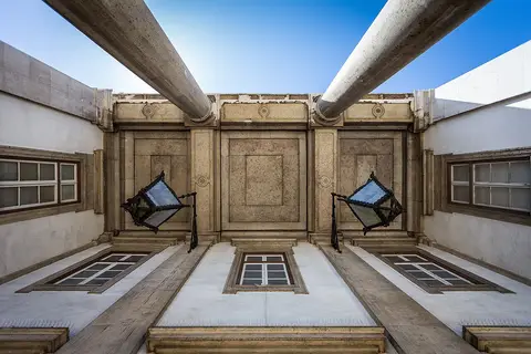 Fachada em pedra do Museu Nacional de História Natural e da Ciência vista de baixo, com lanternas e céu azul