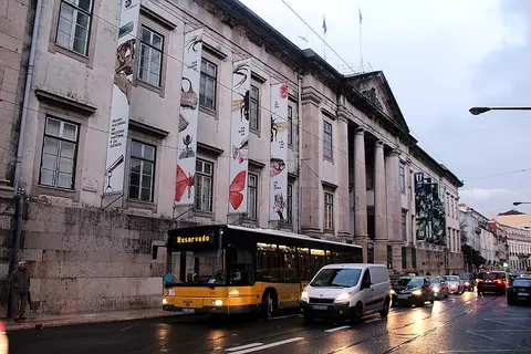 Fachada do Museu Nacional de História Natural e da Ciência em Lisboa, com autocarro e trânsito na rua