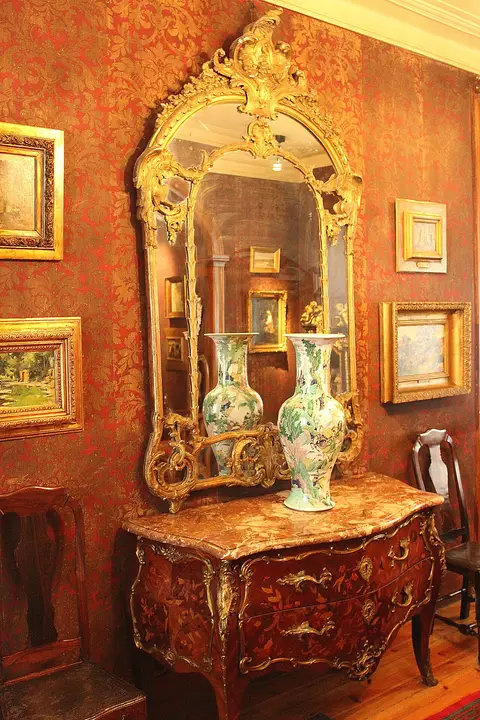Sala vermelha da casa-museu com espelho dourado, cómoda marchetada, jarras de porcelana e quadros