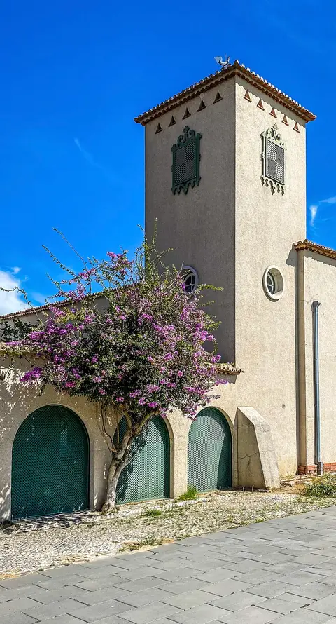 Exterior do Museu de Arte Popular em Belém, com torre e buganvília florida junto às portas em arco