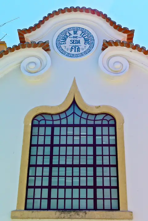 Fachada branca com painel de azulejos "F\u00e1brica de Tecidos de Seda" e janela em arco, Lisboa