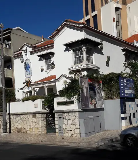 Fachada branca do Museu Bordalo Pinheiro, com painel de azulejos e figuras de cerâmica na parede