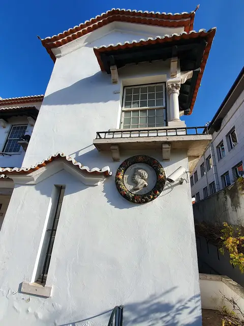 Fachada branca do Museu Bordalo Pinheiro com medalhão em relevo e janela sob telhado de telha