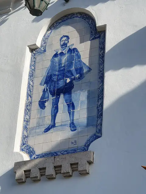 Painel de azulejos azuis com figura masculina na fachada branca do Museu Bordalo Pinheiro