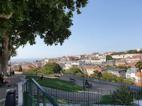 Miradouro do Torel, em Lisboa, com relvado, bancos e vista sobre os telhados da cidade e o rio