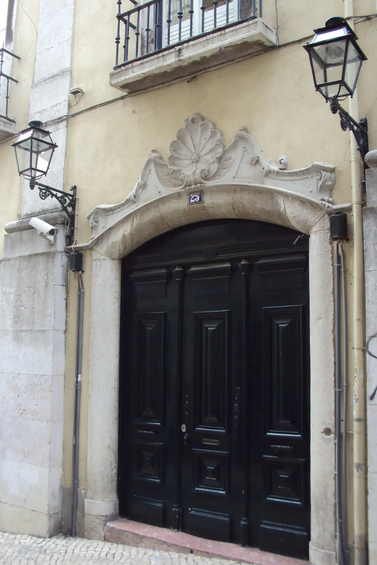 Portal barroco com porta de madeira escura e lanternas na entrada do Grande Oriente Lusitano