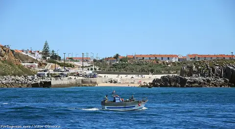 Praia do Porto da Areia Sul, em Peniche, vista do mar, com barco de pesca e casario ao fundo
