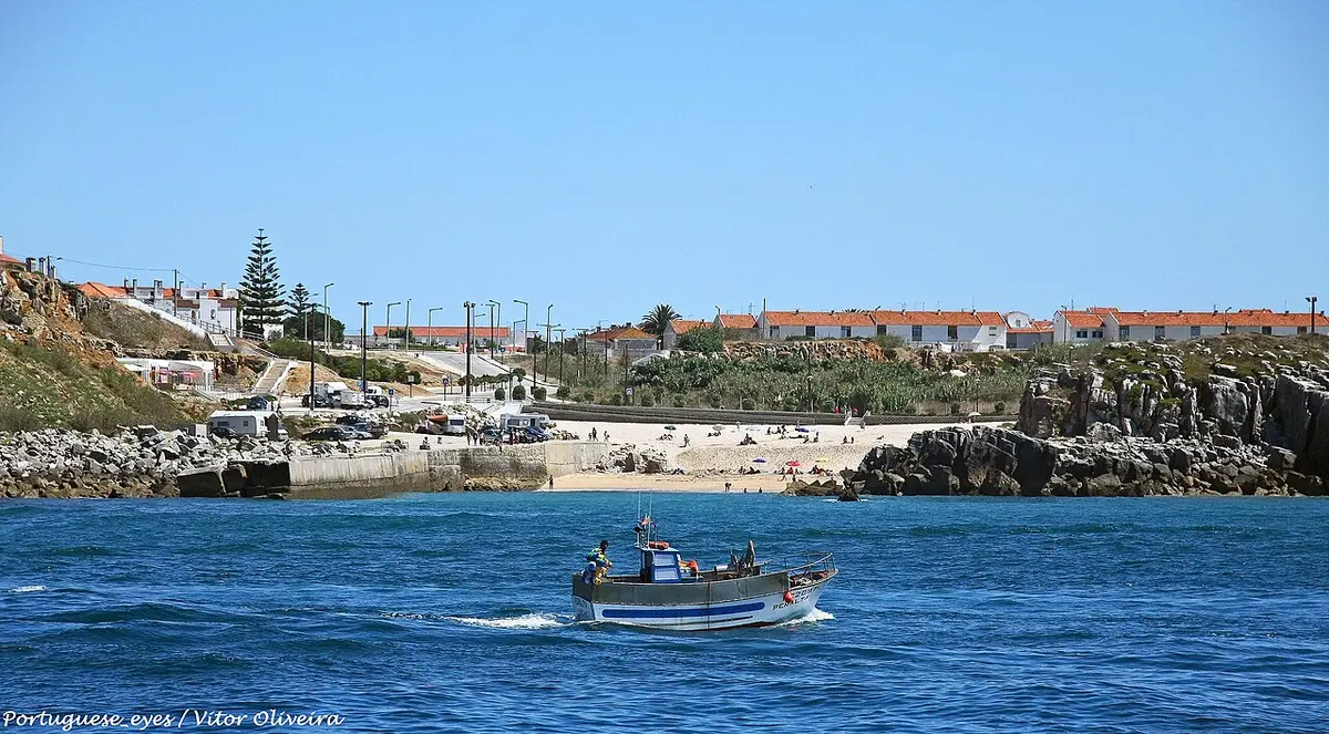 Praia do Porto da Areia Sul, em Peniche, vista do mar, com barco de pesca e casario ao fundo