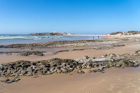 Praia do Baleal com areal, rochas descobertas pela maré baixa e vista para a povoação ao fundo
