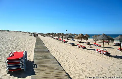 Praia do Pego com passadiço de madeira, chapéus de palha e espreguiçadeiras na areia