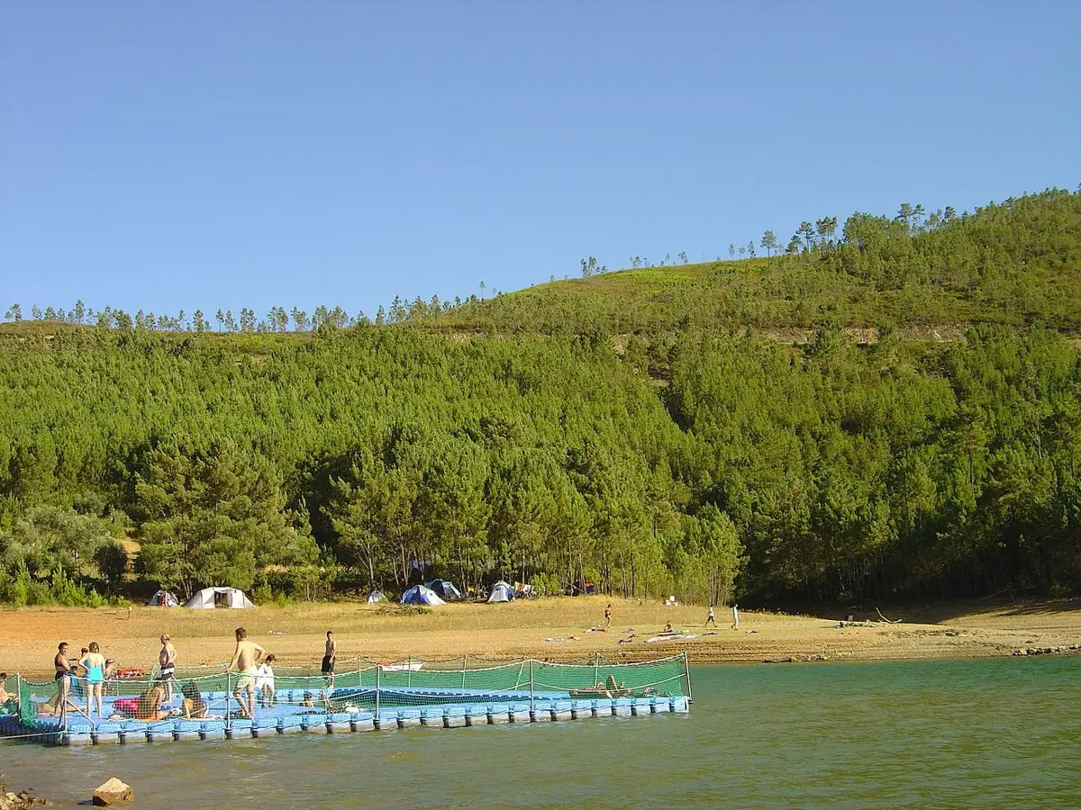 Praia fluvial de Fernandaires na albufeira de Castelo de Bode, com pontão flutuante e encosta arborizada