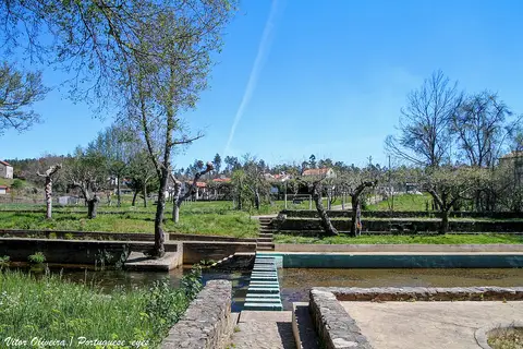 Praia fluvial do Açude do Pinto, com tanque de água, passadiço de pedra e árvores em redor