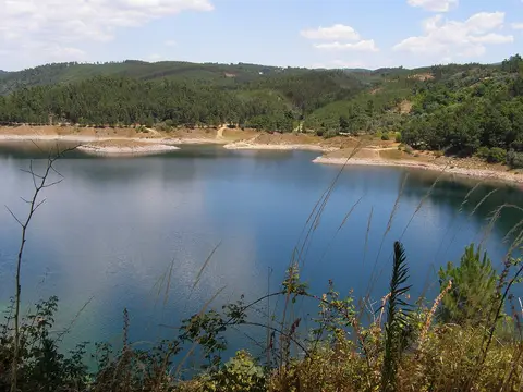 Albufeira da barragem do Cabril com águas azuis rodeadas por encostas de pinhal