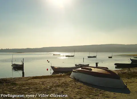 Barcos de madeira na margem da Lagoa de Óbidos, em Foz do Arelho, com contraluz ao pôr do sol