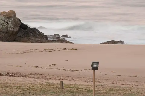 Praia de areia com rochas e mar ao entardecer, junto a Santo André