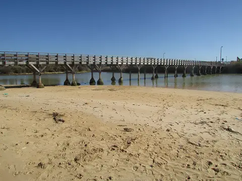 Passadiço de madeira sobre a ribeira de Espiche, visto da areia da praia dos Salgados