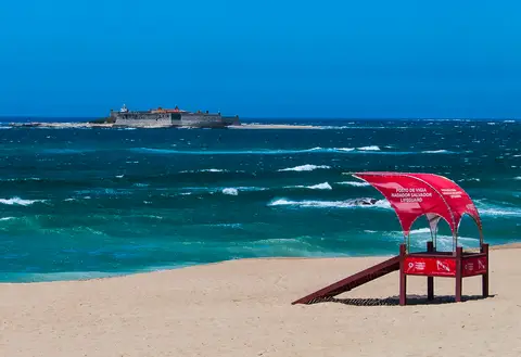 Praia de Moledo com posto de vigia vermelho na areia e a Ínsua ao largo