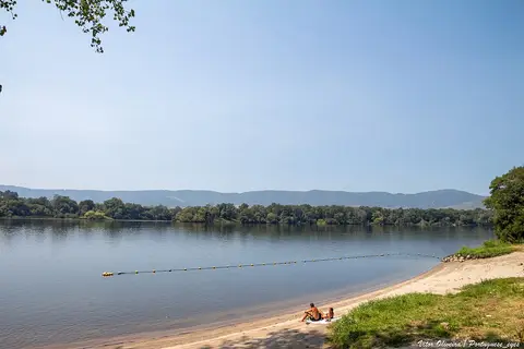 Praia fluvial da Lenta com areia, boias no rio e colinas arborizadas ao fundo