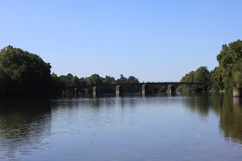 Ponte de pedra sobre o rio Cávado em Prado, com margens arborizadas e água calma
