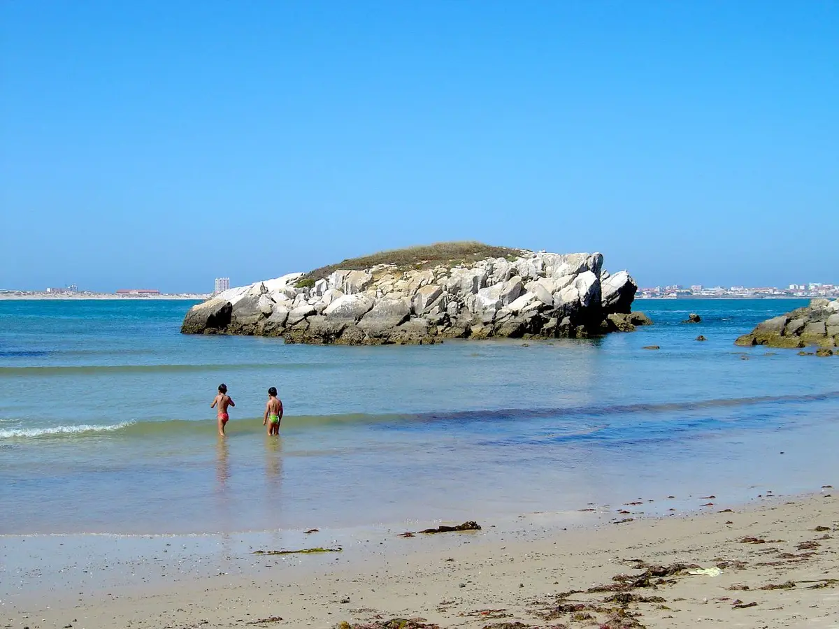 Praia do Baleal com duas crianças ao longe na água e ilhéu rochoso ao fundo