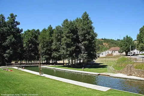 Zona de lazer de Folques com piscina fluvial junto a relvado e árvores, sob céu azul