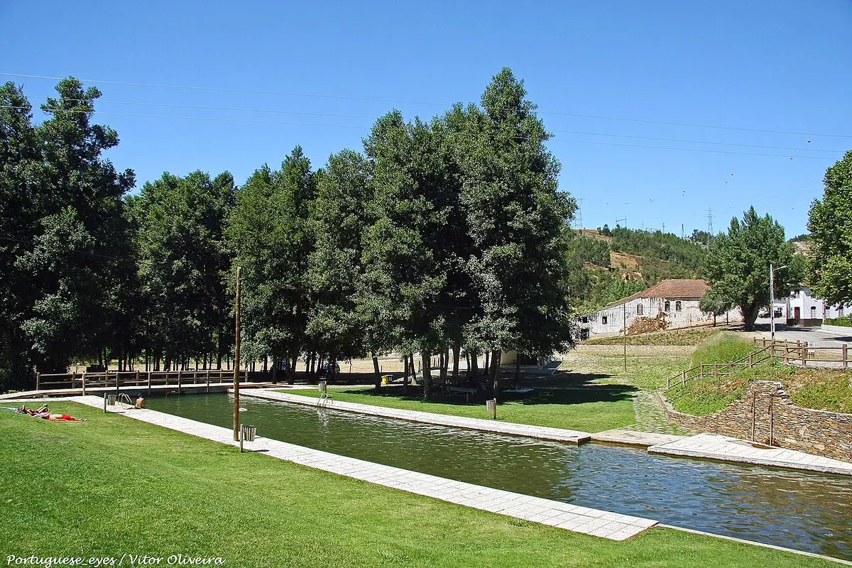 Zona de lazer de Folques com piscina fluvial junto a relvado e árvores, sob céu azul