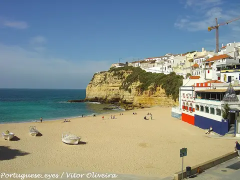 Praia do Carvoeiro com barcos na areia, falésia e casas brancas sobre o mar