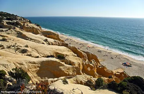 Praia da Galé-Fontaínhas vista do alto, com falésias douradas, areal e mar azul.
