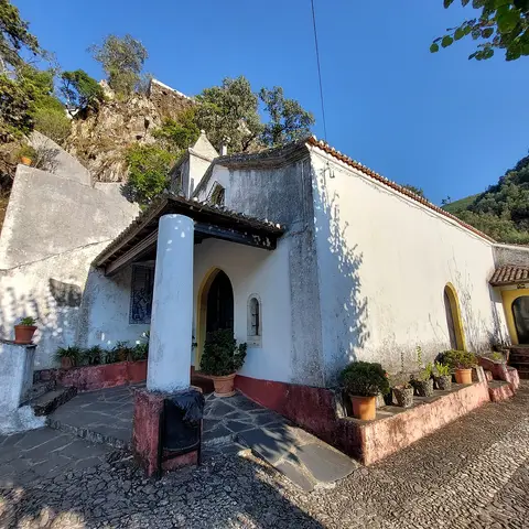 Capela caiada com faixa vermelha e vasos de plantas no santuário da Senhora da Piedade, Lousã