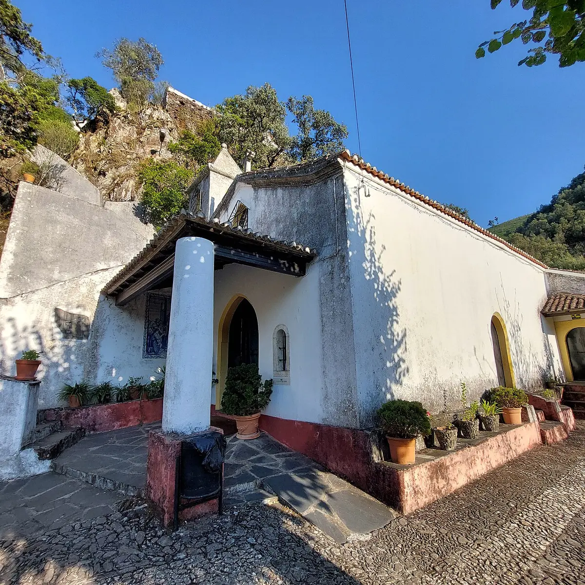 Capela caiada com faixa vermelha e vasos de plantas no santuário da Senhora da Piedade, Lousã