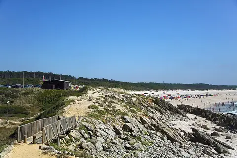 Praia de Pedrógão com passadiço de madeira, dunas, rochas e banhistas ao longe