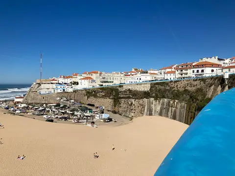 Praia dos Pescadores na Ericeira, com areal amplo, barcos e casas brancas sobre a arriba