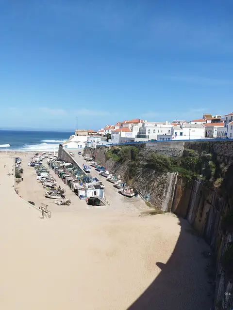Praia dos Pescadores na Ericeira, com areal, barcos de pesca e casas brancas sobre a falésia