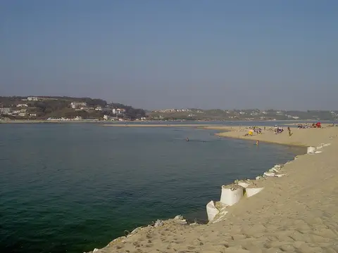 Praia do Bom Sucesso junto à Lagoa de Óbidos, com areal, sacos de areia e banhistas ao longe