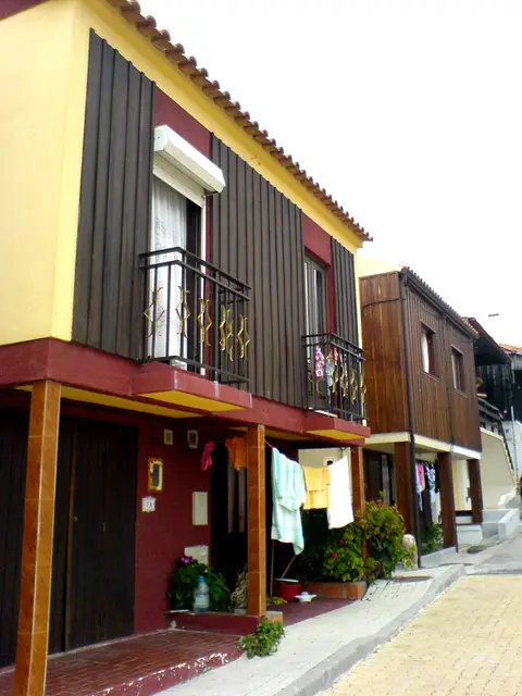 Casas tradicionais de madeira com varandas numa rua da Tocha