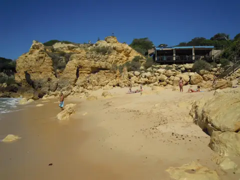 Praia do Castelo em Albufeira, com falésias douradas, areia dourada e esplanada sobre as rochas