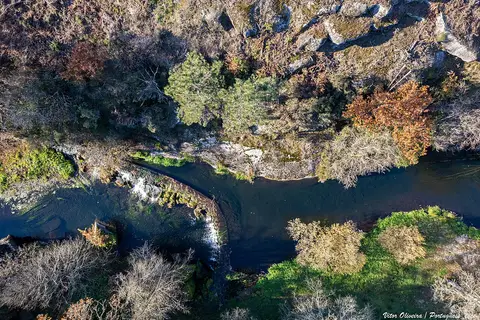 Vista aérea de um rio com açude, rochas e vegetação na zona de lazer da Ucha