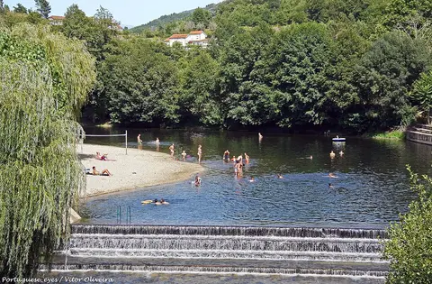 Praia fluvial de São Sebastião da Feira com açude em degraus, areal e banhistas ao longe no rio