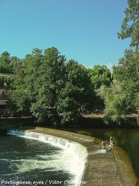 Açude da praia fluvial de Côja com queda de água, rio e árvores em redor