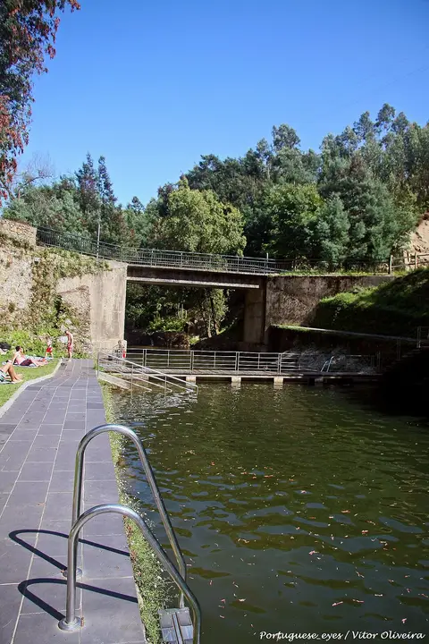 Praia fluvial de Louçainha com tanque de água, escada metálica, deck e ponte sobre o rio