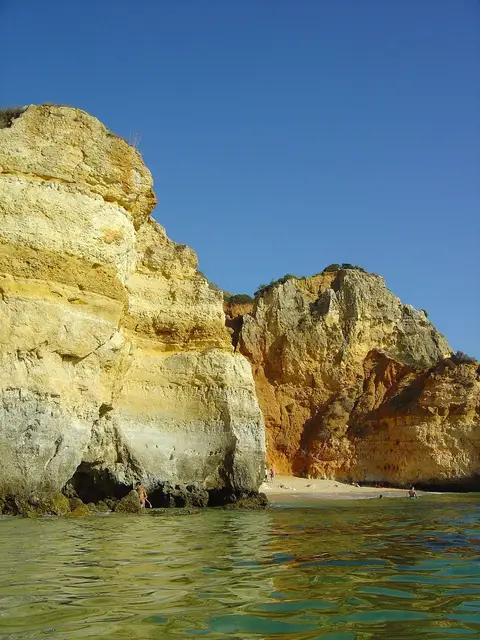 Falésias douradas e água turquesa numa pequena praia do Algarve, vista do mar